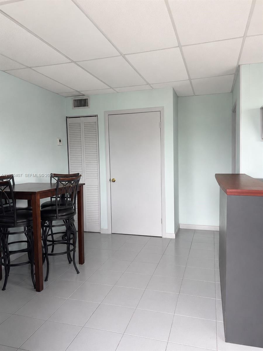 A dining area features a dark wood table, metal chairs, and light-colored tile flooring — OAKLAND PARK, FL