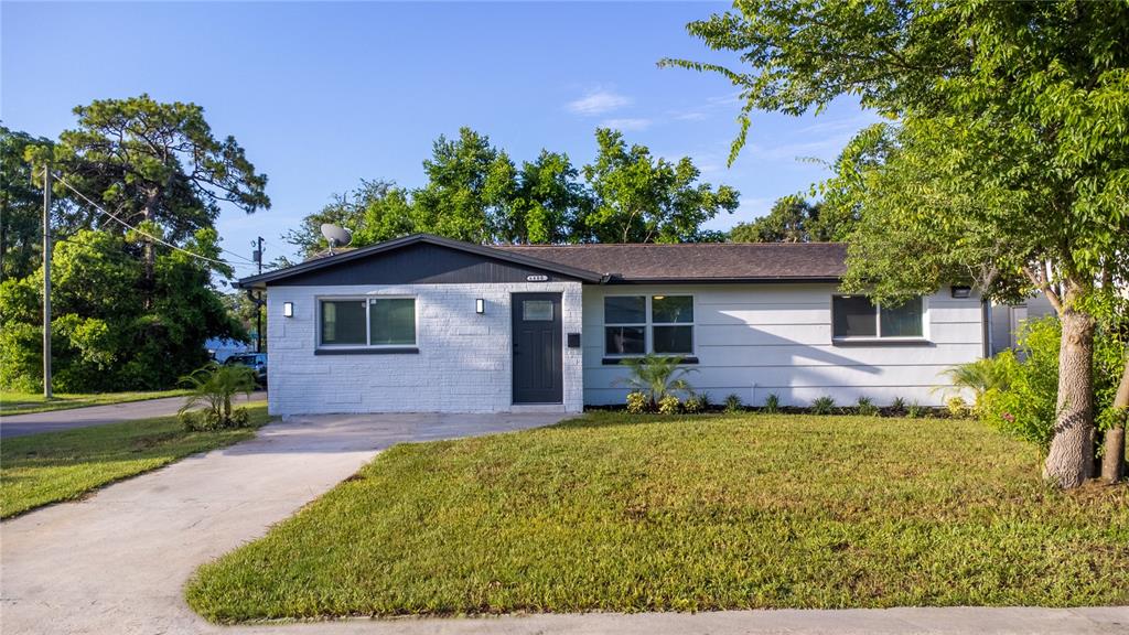 A single-story white brick house with a dark gray door and roof under a blue sky — 6400 MONTANA AVENUE, NEW PORT RICHEY, FL