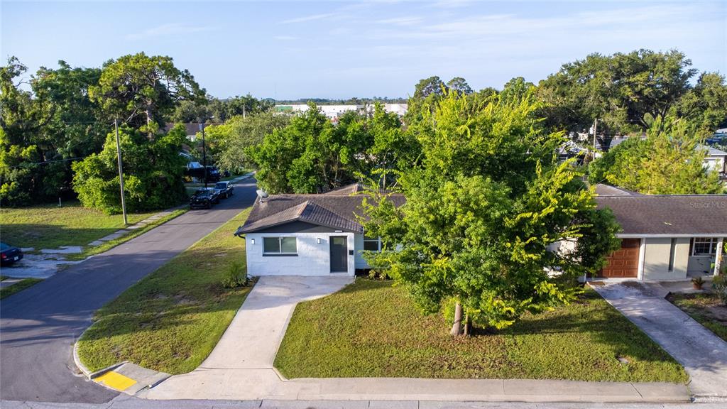An aerial view shows a single-story house with a white exterior, gray roof, and front lawn — 6400 MONTANA AVENUE, NEW PORT RICHEY, FL