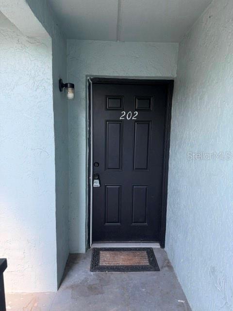 A black front door with the number 202 is set in a light blue exterior wall — 14413 AMERICANA CIRCLE UNIT 202, TAMPA, FL