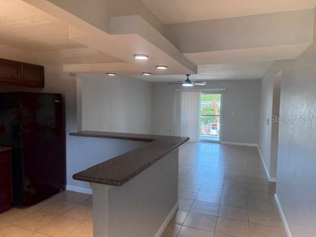 A kitchen with a breakfast bar overlooks a living area with tile floors and balcony access — 14413 AMERICANA CIRCLE UNIT 202, TAMPA, FL