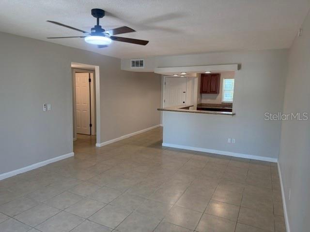 A living room with tile flooring, a ceiling fan, and a pass-through to the kitchen — 14413 AMERICANA CIRCLE UNIT 202, TAMPA, FL