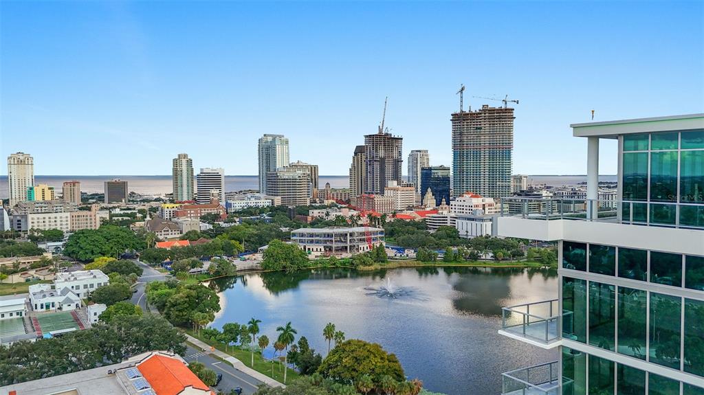 An elevated view of a city skyline overlooking a lake with a modern glass building — 777 3RD AVENUE N UNIT 805, ST PETERSBURG, FL