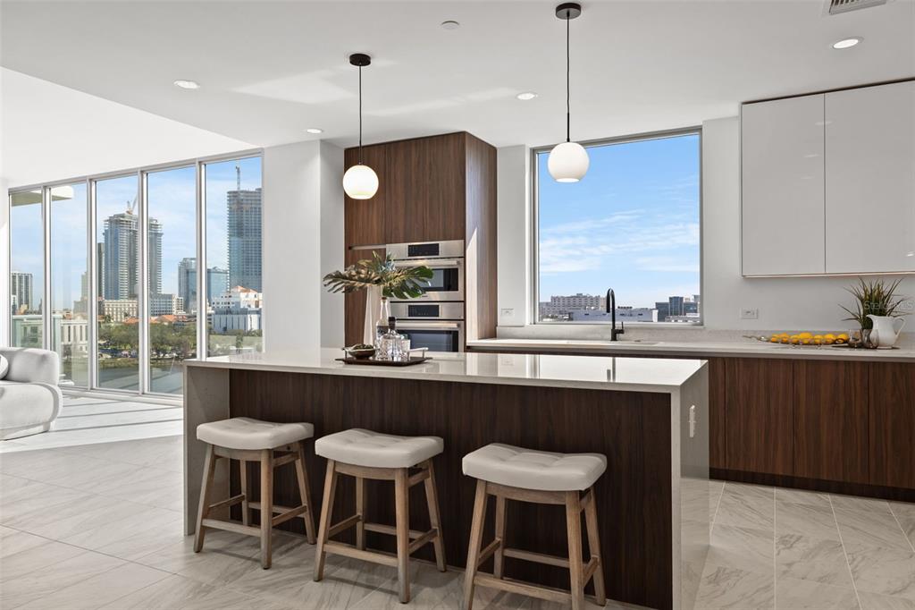 A modern kitchen features a wood-paneled island, white cabinetry, and floor-to-ceiling windows overlooking a city — 777 3RD AVENUE N UNIT 805, ST PETERSBURG, FL