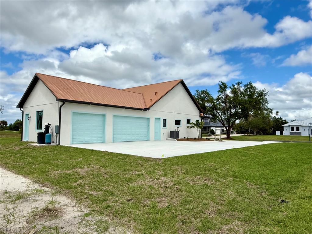 A white detached garage with a copper-colored metal roof and light blue doors — 520 WOODSTORK LANE, PUNTA GORDA, FL