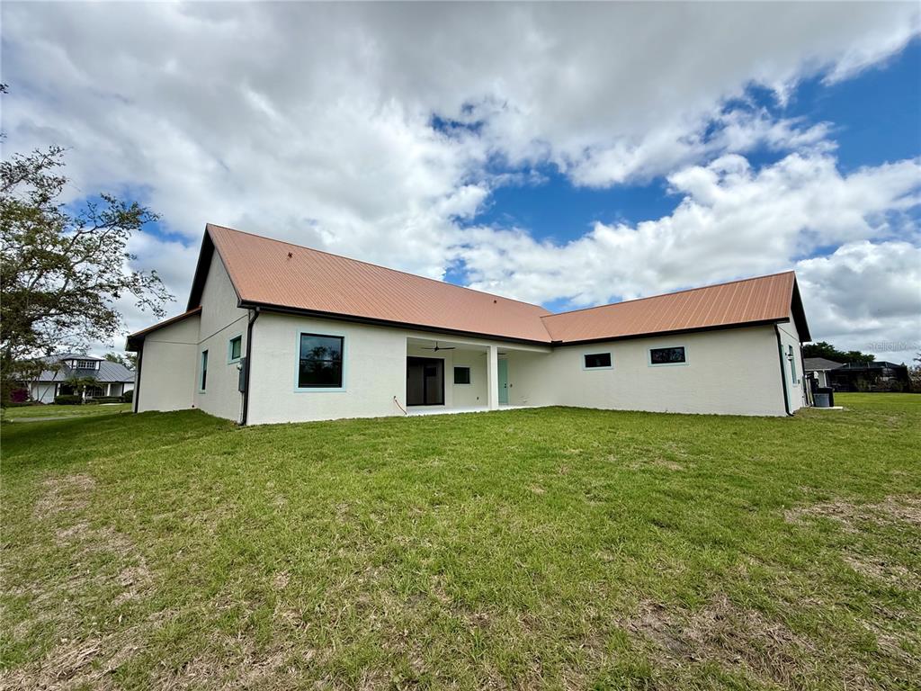 The exterior of a white house with a metal roof and a covered patio area — 520 WOODSTORK LANE, PUNTA GORDA, FL