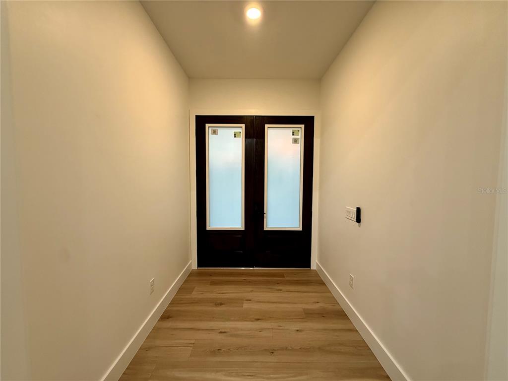 A narrow entryway features light wood-look flooring, white walls, and dark double front doors — 520 WOODSTORK LANE, PUNTA GORDA, FL