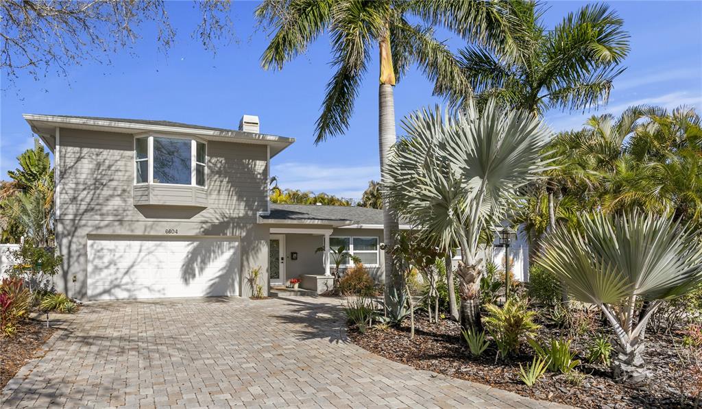 A two-story house with gray siding, a paved driveway, and tropical landscaping — 6604 BLUE HERON DRIVE S, ST PETERSBURG, FL