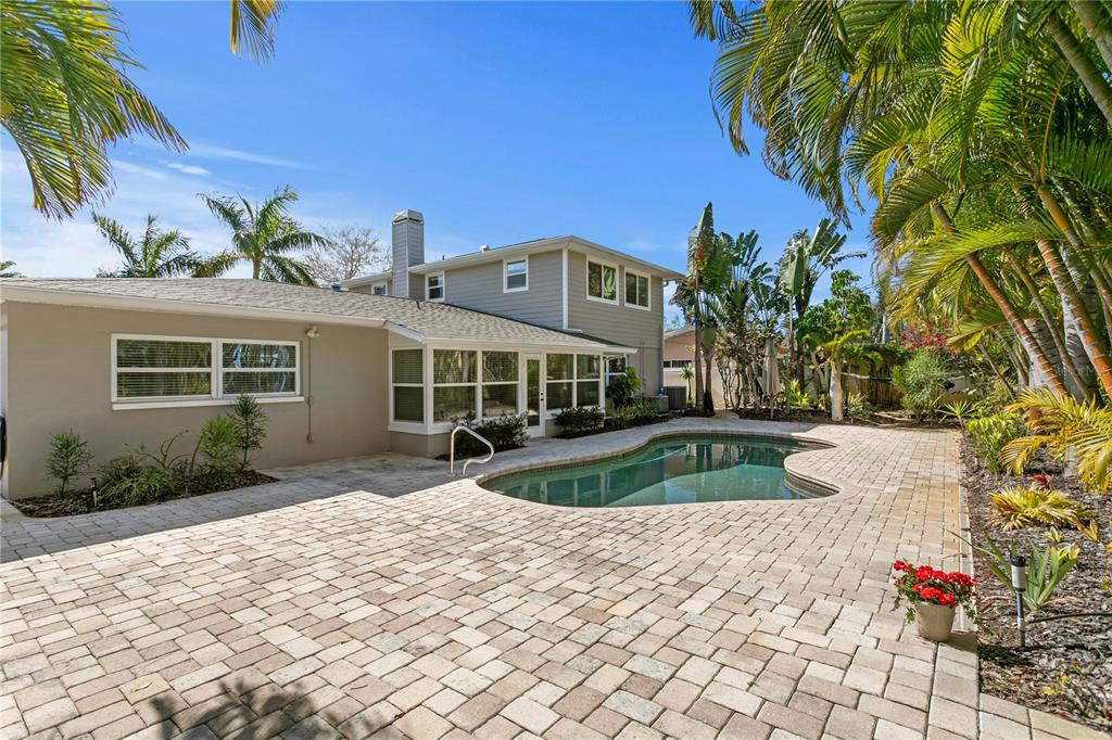 A two-story house with a beige exterior, a paver patio, and a kidney-shaped swimming pool — 6604 BLUE HERON DRIVE S, ST PETERSBURG, FL