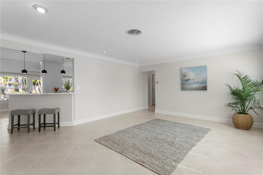 A bright, open-concept living area features light tile flooring, a rug, and a kitchen pass-through — 6604 BLUE HERON DRIVE S, ST PETERSBURG, FL