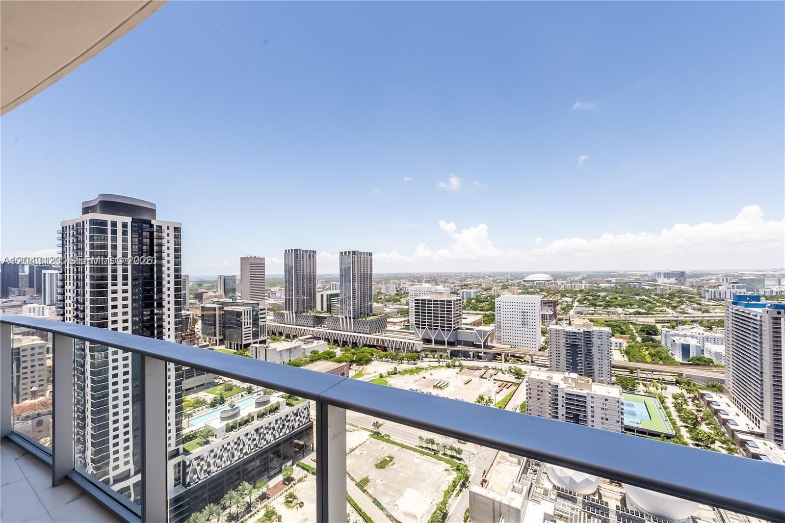 A high-rise balcony overlooks a dense urban cityscape with modern skyscrapers and surrounding infrastructure — 851 NE 1st Ave # 3308, Miami FL 33132, MIAMI, FL