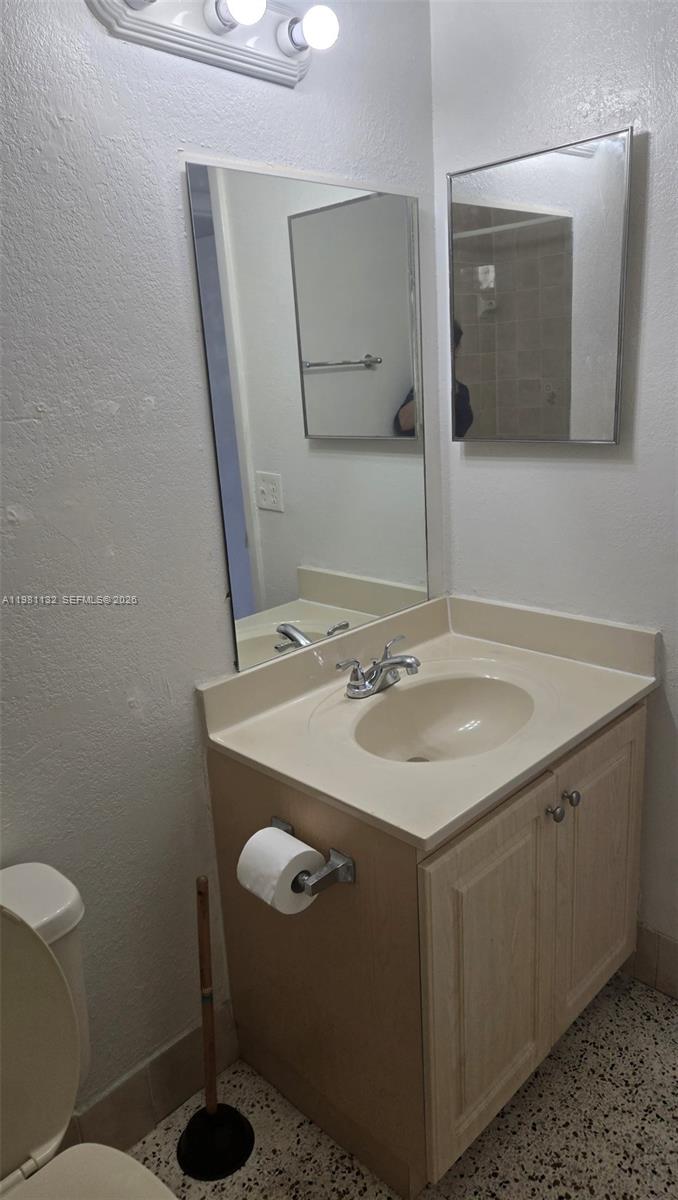A bathroom features a vanity with a beige countertop, a mirror, and a toilet — 142 SW 18th ave # 30, Miami FL 33135, MIAMI, FL