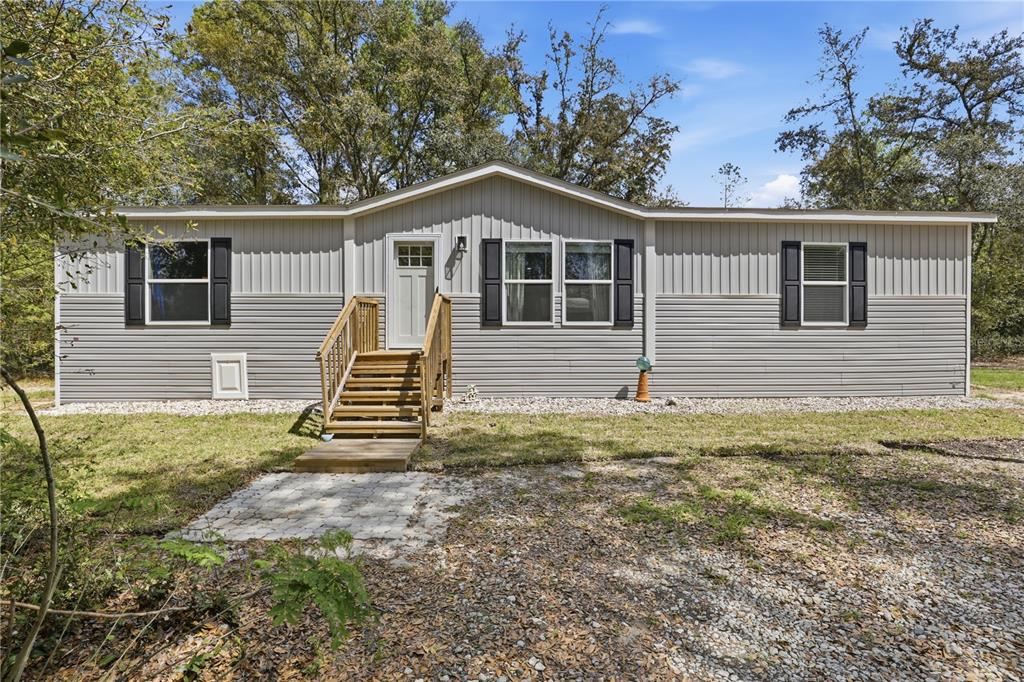 A modern kitchen features light wood cabinetry, a large island with a sink, and stainless appliances — 29578 SW 63RD AVENUE, NEWBERRY, FL
