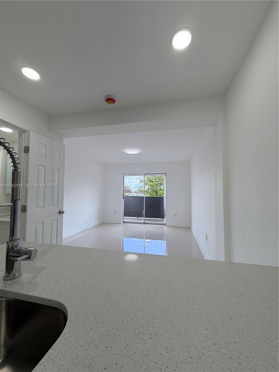 A view from a kitchen counter looking toward a bright room with a sliding door — 1551 W Okeechobee Rd # 9, Hialeah FL 33010, HIALEAH, FL