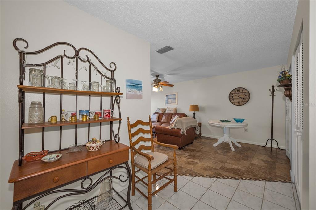A dining area with a metal baker's rack, a wooden chair, and a round table — 2700 BAYSHORE BOULEVARD UNIT 6107, DUNEDIN, FL