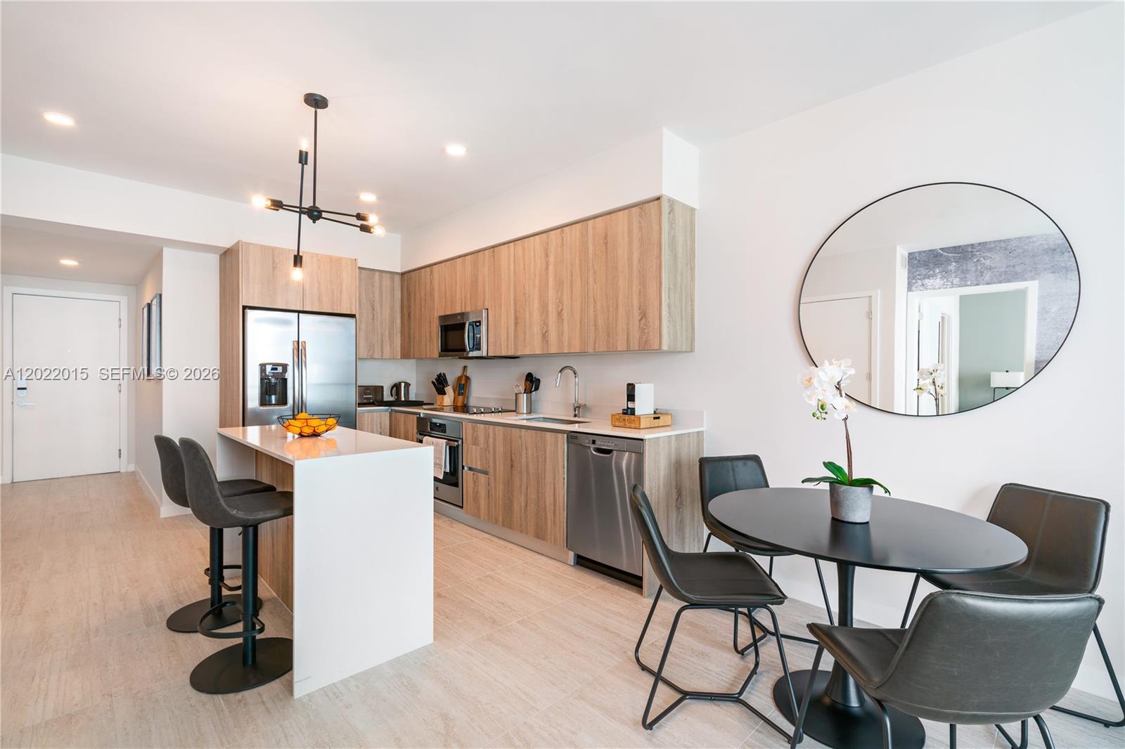 A modern kitchen features light wood cabinetry, a white island, and an adjacent dining area — 3900 Biscayne Blvd # 818, Miami FL 33137, MIAMI, FL