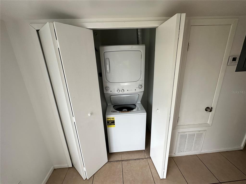 A white stacked washer and dryer unit sits inside a closet with folding doors — 3544 KHAYYAM AVENUE, ORLANDO, FL