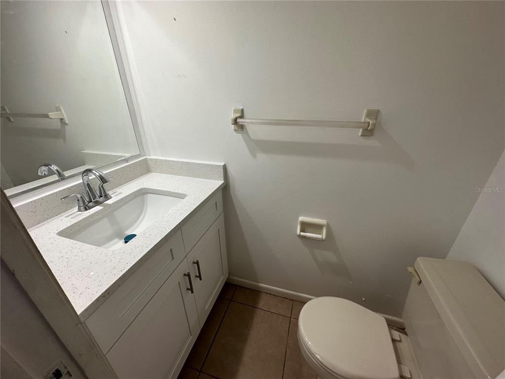 A bathroom features a white vanity with a speckled countertop, a toilet, and a towel bar — 3544 KHAYYAM AVENUE, ORLANDO, FL