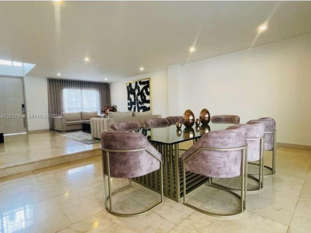 A dining area with a glass table and velvet chairs sits next to a living room — 20 ST Loma Montesori Poblado, CO, CO