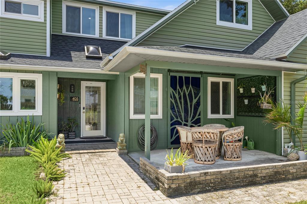 A green house exterior features a front porch with a patio set and brick pavers — 405 BAY POINT AVENUE, NOKOMIS, FL