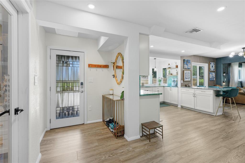 An entryway with a glass-paneled door leads into an open-concept kitchen with white cabinetry — 405 BAY POINT AVENUE, NOKOMIS, FL