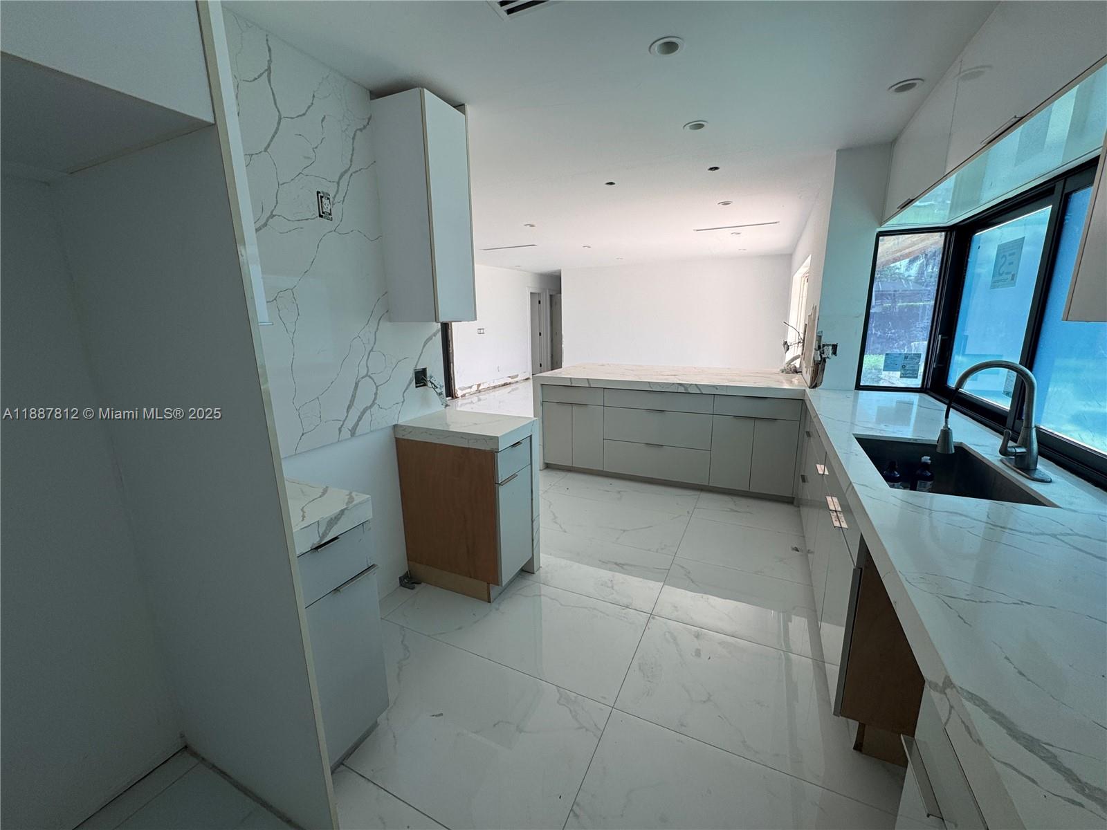 A modern kitchen features white marble-veined countertops, light gray cabinetry, and large white floor tiles — 444 NW 21st St, Homestead FL 33030, HOMESTEAD, FL