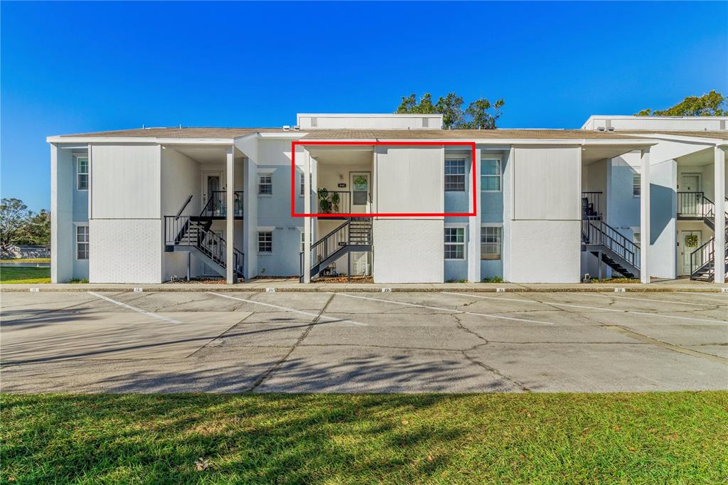 A two-story apartment building exterior features white siding, stairs, and a highlighted upper-level unit — 3823 N OAK DRIVE UNIT K22, TAMPA, FL
