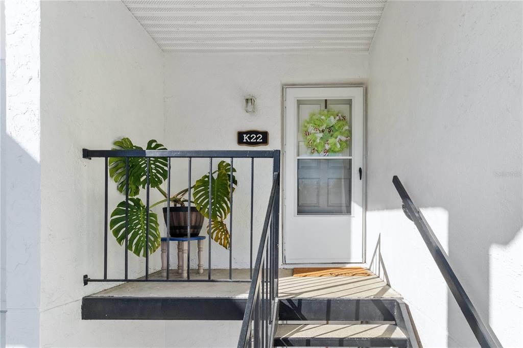An exterior view of a residential entryway with a black railing, stairs, and a door — 3823 N OAK DRIVE UNIT K22, TAMPA, FL