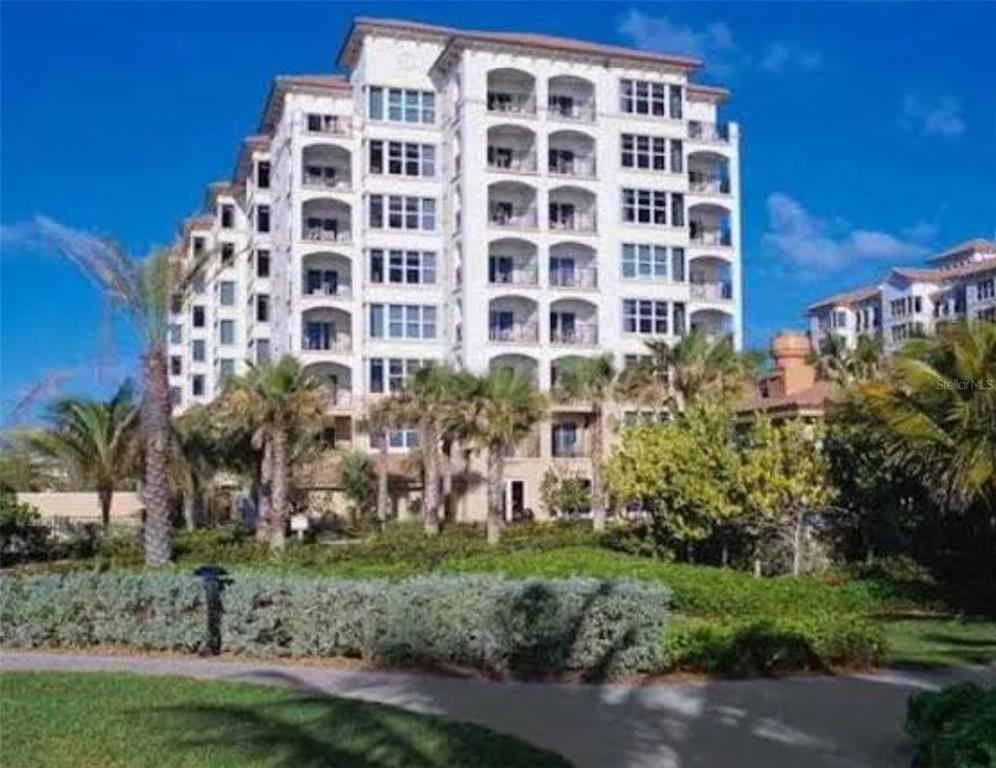 A multi-story white residential building stands behind palm trees and landscaped grounds — 71 S OCEAN AVENUE UNIT 8708, PALM BEACH SHORES, FL