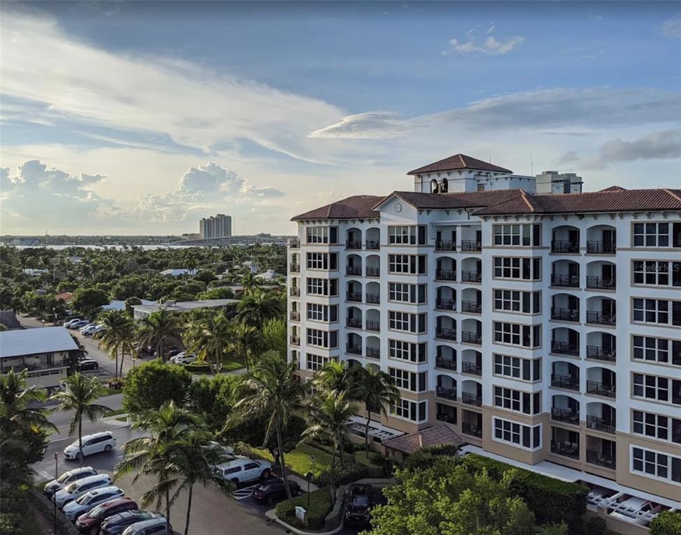 An exterior view of a multi-story apartment building surrounded by palm trees and parking lots — 71 S OCEAN AVENUE UNIT 8708, PALM BEACH SHORES, FL