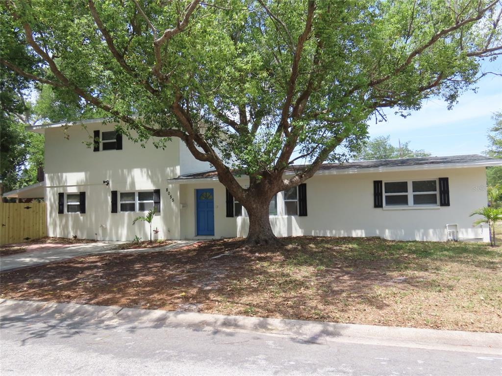A two-story house with a blue front door and a large tree in the yard — 8055 33RD AVENUE N, ST PETERSBURG, FL