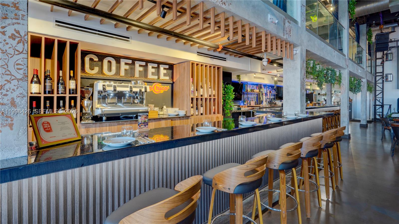 A modern bar area features a long black counter, wooden stools, and a coffee station — Restaurant for Sale, Miami FL 33135, MIAMI, FL