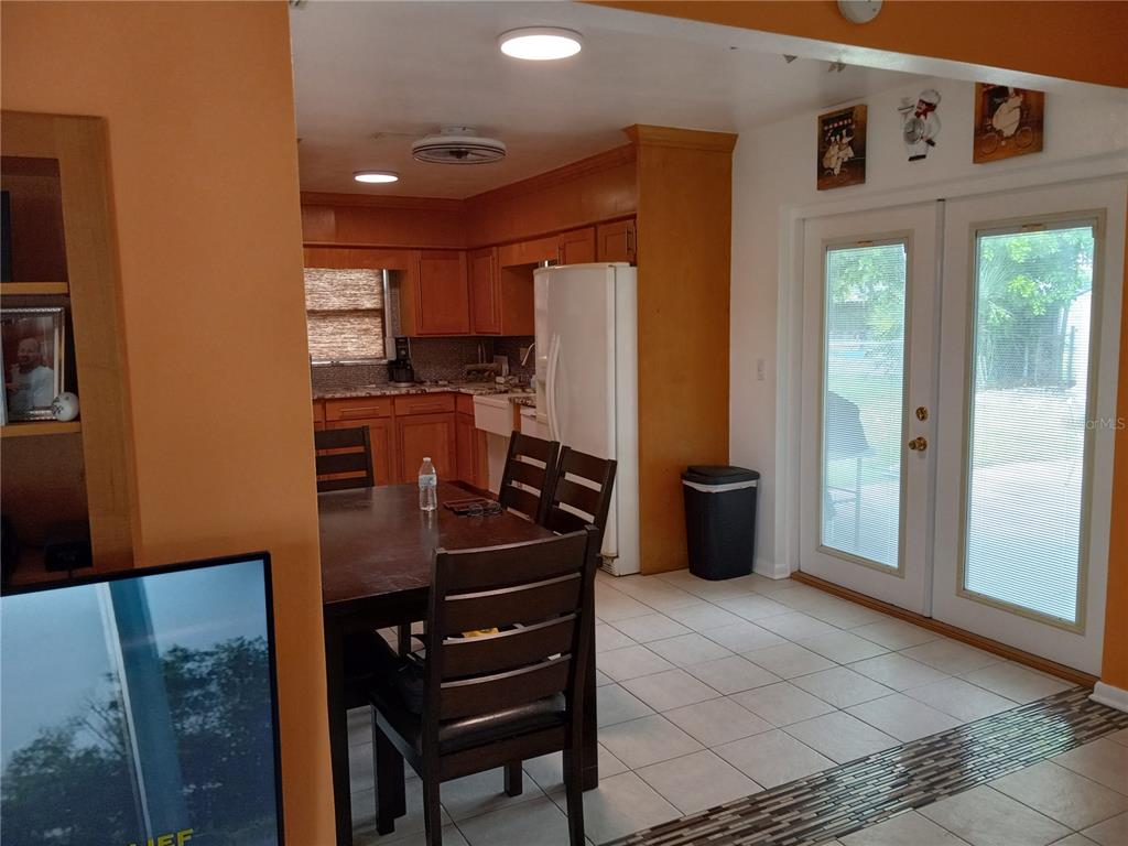 A dining area with a wooden table and chairs leads into a kitchen with wooden cabinets — 240 REGINA DRIVE S, LARGO, FL