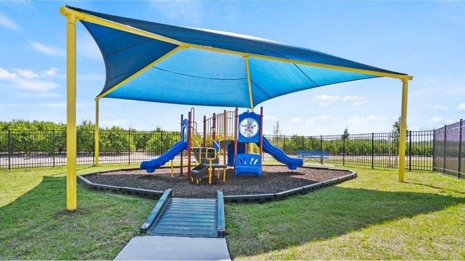 A playground with a blue shade canopy, slides, and climbing equipment sits on a grassy lot — 3013 CAPTAIN JAX WAY, WINTER HAVEN, FL