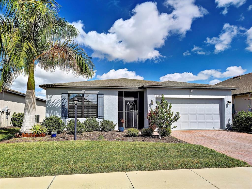 A single-story house with a palm tree, a two-car garage, and a paved driveway — 2065 APIAN WAY, PORT CHARLOTTE, FL