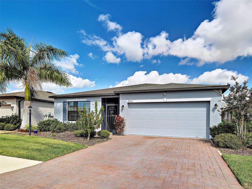 A single-story house with a two-car garage, a paved driveway, and a palm tree — 2065 APIAN WAY, PORT CHARLOTTE, FL