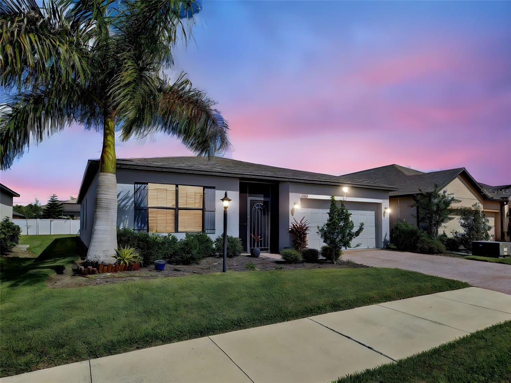A single-story house with a palm tree, a two-car garage, and a sunset sky — 2065 APIAN WAY, PORT CHARLOTTE, FL