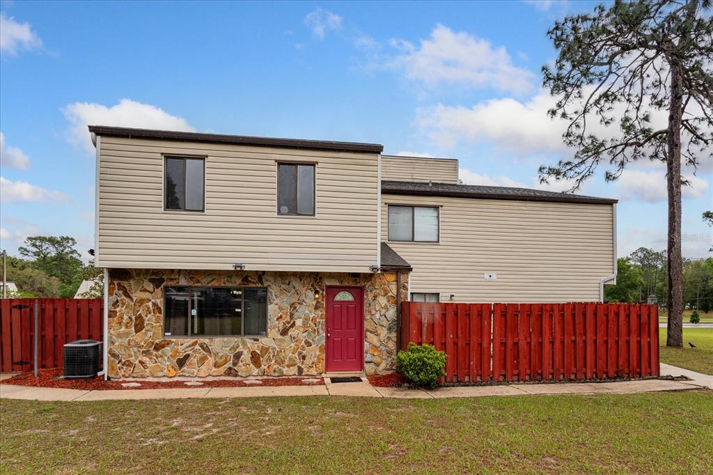A two-story house with tan siding, a stone facade, and a red front door — 2134 NE 45TH AVENUE, OCALA, FL