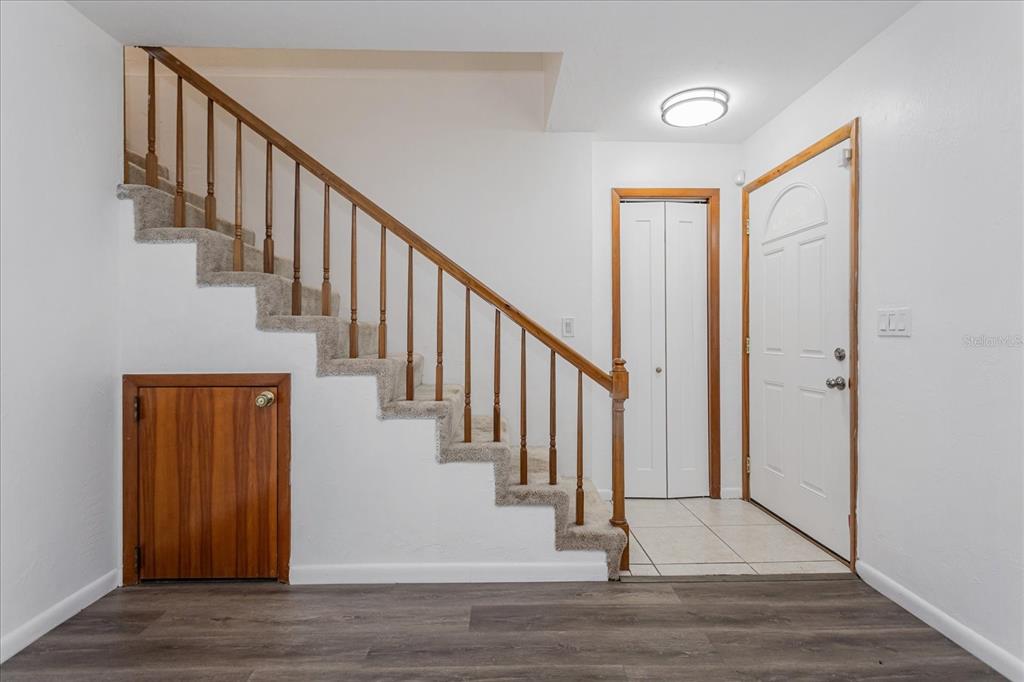 An entryway features a carpeted staircase with a wooden railing, a storage door, and tile flooring — 2134 NE 45TH AVENUE, OCALA, FL
