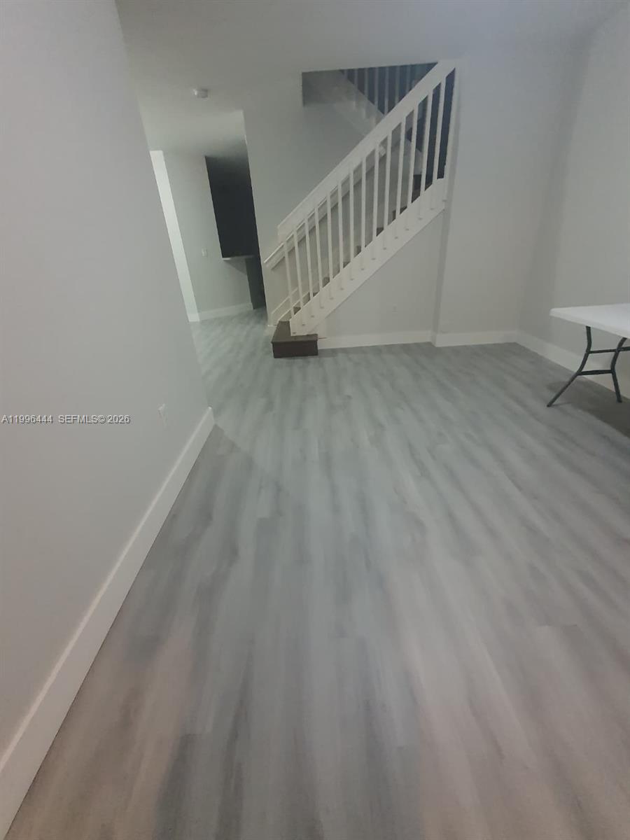 This room features light gray wood-look flooring, white walls, and a white staircase — 16648 SW 83rd Ln # 16648, Miami FL 33193, MIAMI, FL