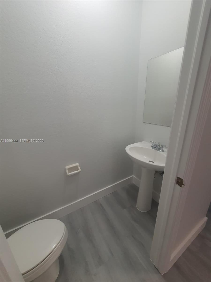 A small bathroom features a pedestal sink, a toilet, and light-colored wood-look flooring — 16648 SW 83rd Ln # 16648, Miami FL 33193, MIAMI, FL
