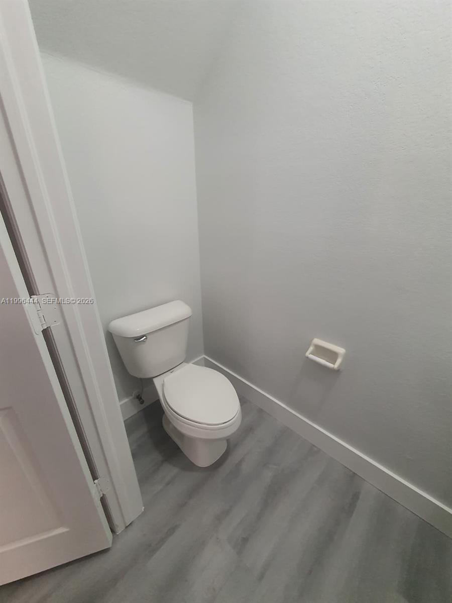 A small bathroom features a white toilet, gray wood-look flooring, and light gray walls — 16648 SW 83rd Ln # 16648, Miami FL 33193, MIAMI, FL