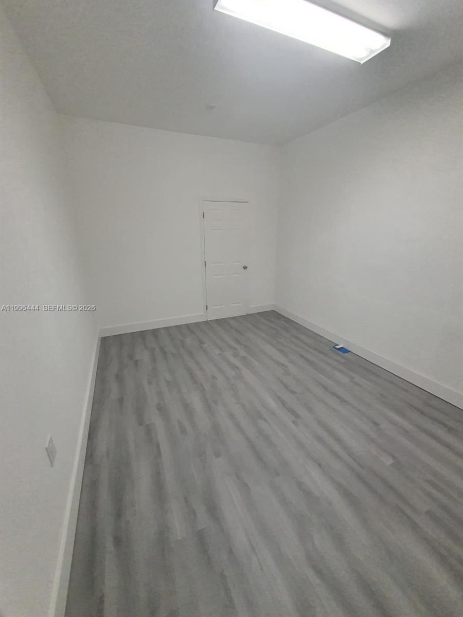 An empty room features white walls, a single door, and light gray wood-look flooring — 16648 SW 83rd Ln # 16648, Miami FL 33193, MIAMI, FL