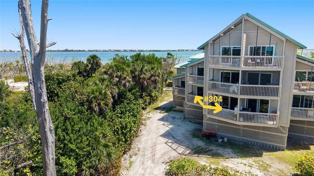 An exterior view of a multi-story building with balconies overlooking a coastal landscape — 9200 LITTLE GASPARILLA UNIT 304, PLACIDA, FL