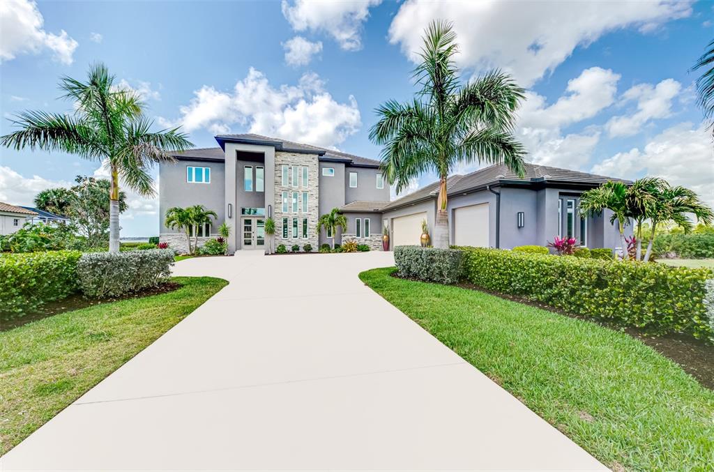 A two-story gray house with a stone facade, palm trees, and a concrete driveway — 3051 RIVERSHORE LANE, PORT CHARLOTTE, FL