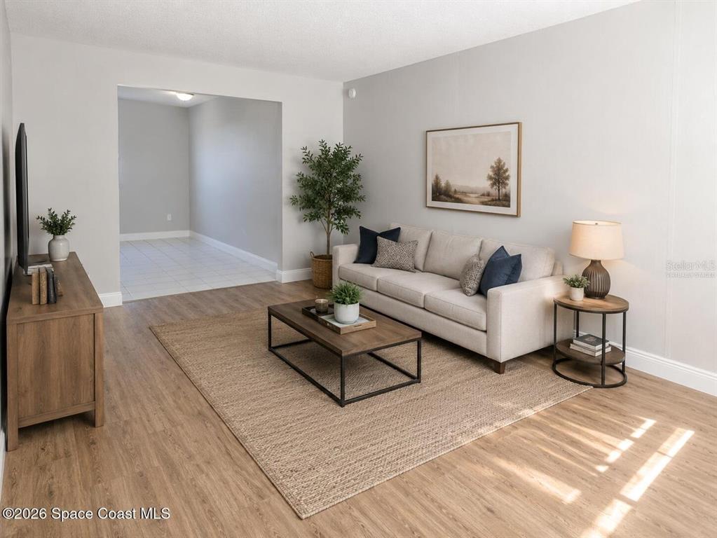 A living room features light wood flooring, a beige sofa, and a wooden coffee table — 50 NEEDLE BOULEVARD UNIT 6, MERRITT ISLAND, FL