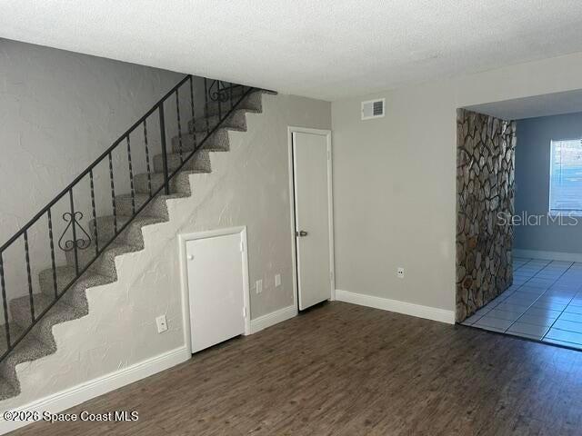 A room features a carpeted staircase with a metal railing, wood-look flooring, and a stone wall — 50 NEEDLE BOULEVARD UNIT 6, MERRITT ISLAND, FL