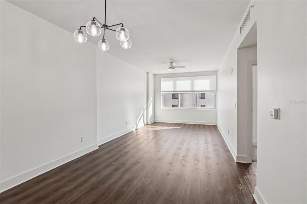 An empty room with white walls, dark wood-look flooring, a chandelier, and a ceiling fan — 1208 E KENNEDY BOULEVARD UNIT 616, TAMPA, FL