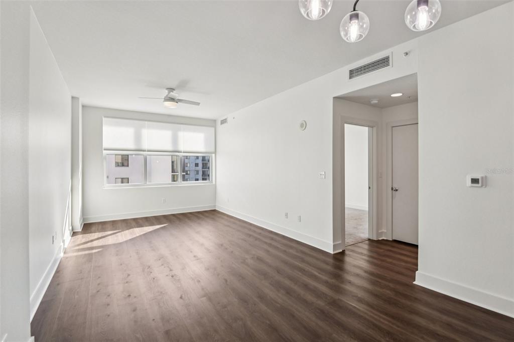 An empty living room with white walls, wood-look flooring, a ceiling fan, and large windows — 1208 E KENNEDY BOULEVARD UNIT 616, TAMPA, FL