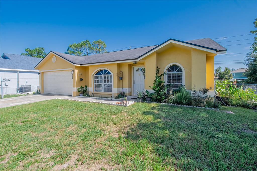 A yellow single-story house with a two-car garage and arched windows under a clear sky — 7212 PEBBLE PASS LOOP, LAKELAND, FL